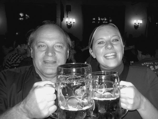 Smiling man and woman raise large beer mugs in a tavern