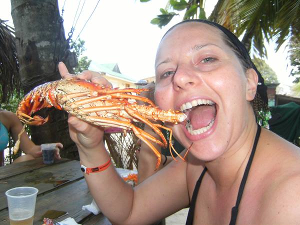 Woman pretending to bite a lobster at an open-air tavern