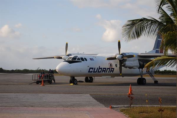 Cubana twin-engine propeller plane parked on tarmac among palm trees and cones