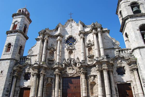 Baroque coral-stone facade of Havana Cathedral, bell towers under a blue sky