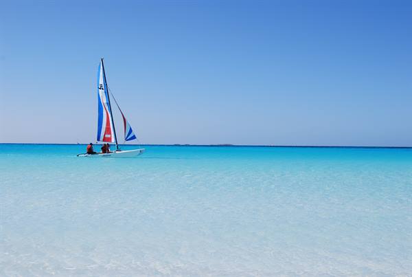 Person on colorful sailboat in clear turquoise water
