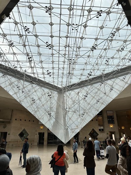 Under the Louvre's inverted pyramid, a moment of shared wonder.