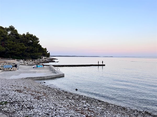Pink sunset over the sea, soft skies from the pier of Zadar.