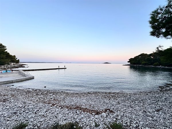 Pink sunset over the bay: the calm sea and the evening slowly falling.
