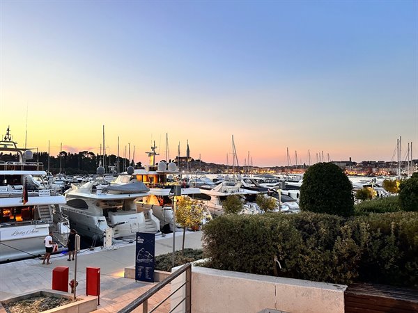 Sunset over the port of Rovinj, among yachts and lights turning on.
