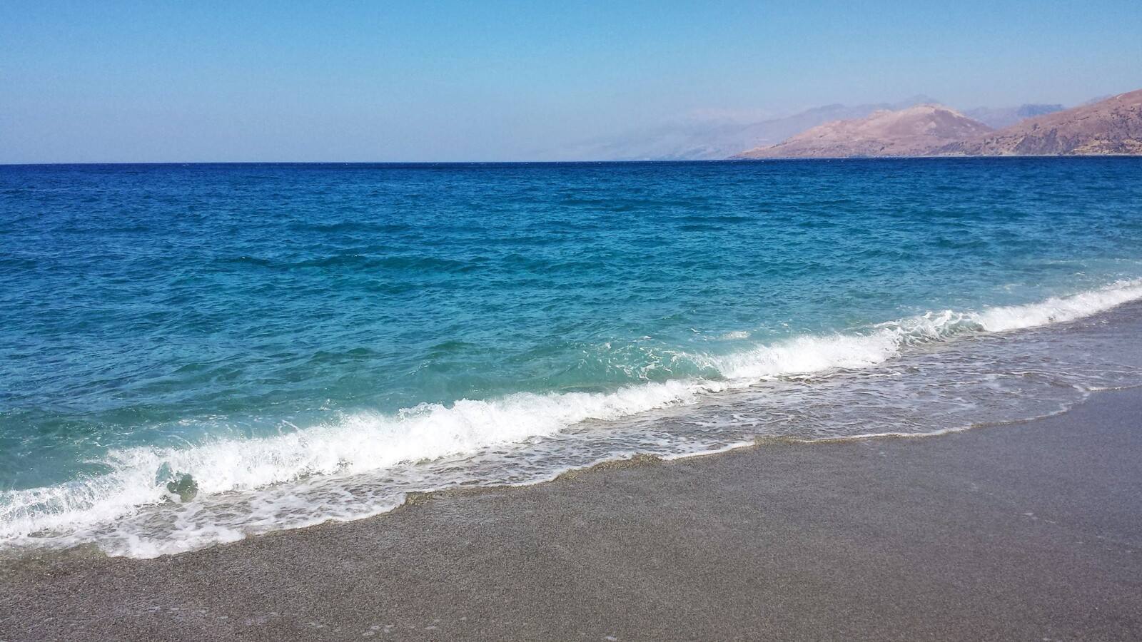 Il mare che accarezza la riva, momente di pura serenità greca.