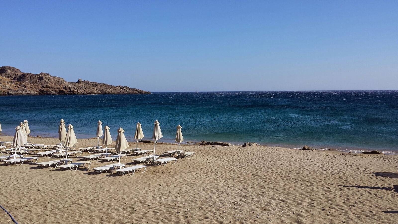 La spiaggia ancora silenziosa, ombrelloni che aspettano il sole della giornata.