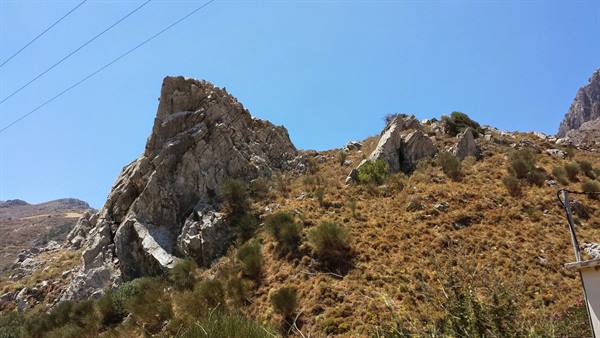 Arid hills and steep rocks under an endless blue sky.