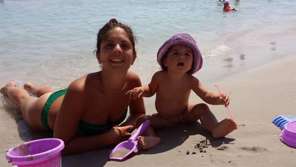 Playing with the sand at the sea, smiling and full of sunshine.
