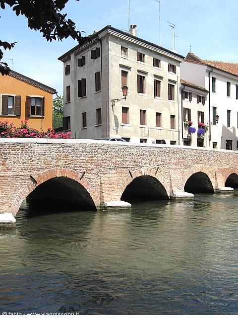Brick bridge with five arches over canal, old painted houses
