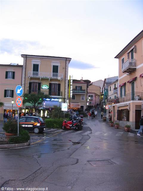 Square with carabinieri car and motorcycles among colorful buildings in Marina di Campo