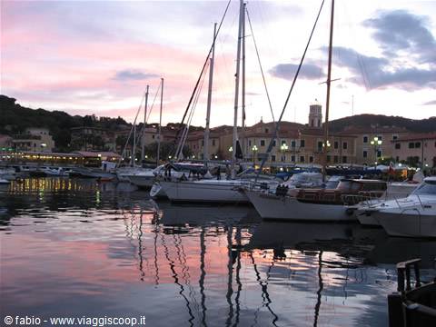 Sailboat masts mirrored in pink dawn water at Portoferraio harbor