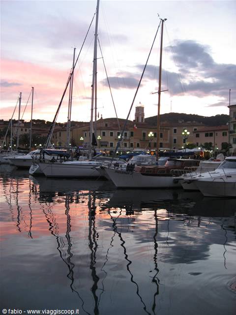 Sailboats moored at Portoferraio harbor, masts mirrored in pink water