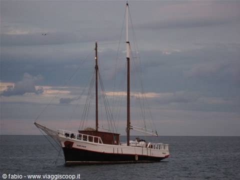 Two-masted schooner anchored at sea under cloudy sky