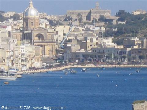 Harbour with boats and stone dome in front of Malta's buildings