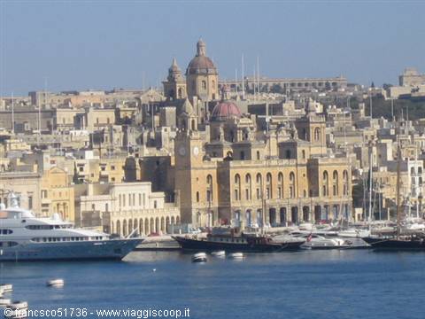 Yachts moored in front of Valletta's limestone waterfront under clear sky