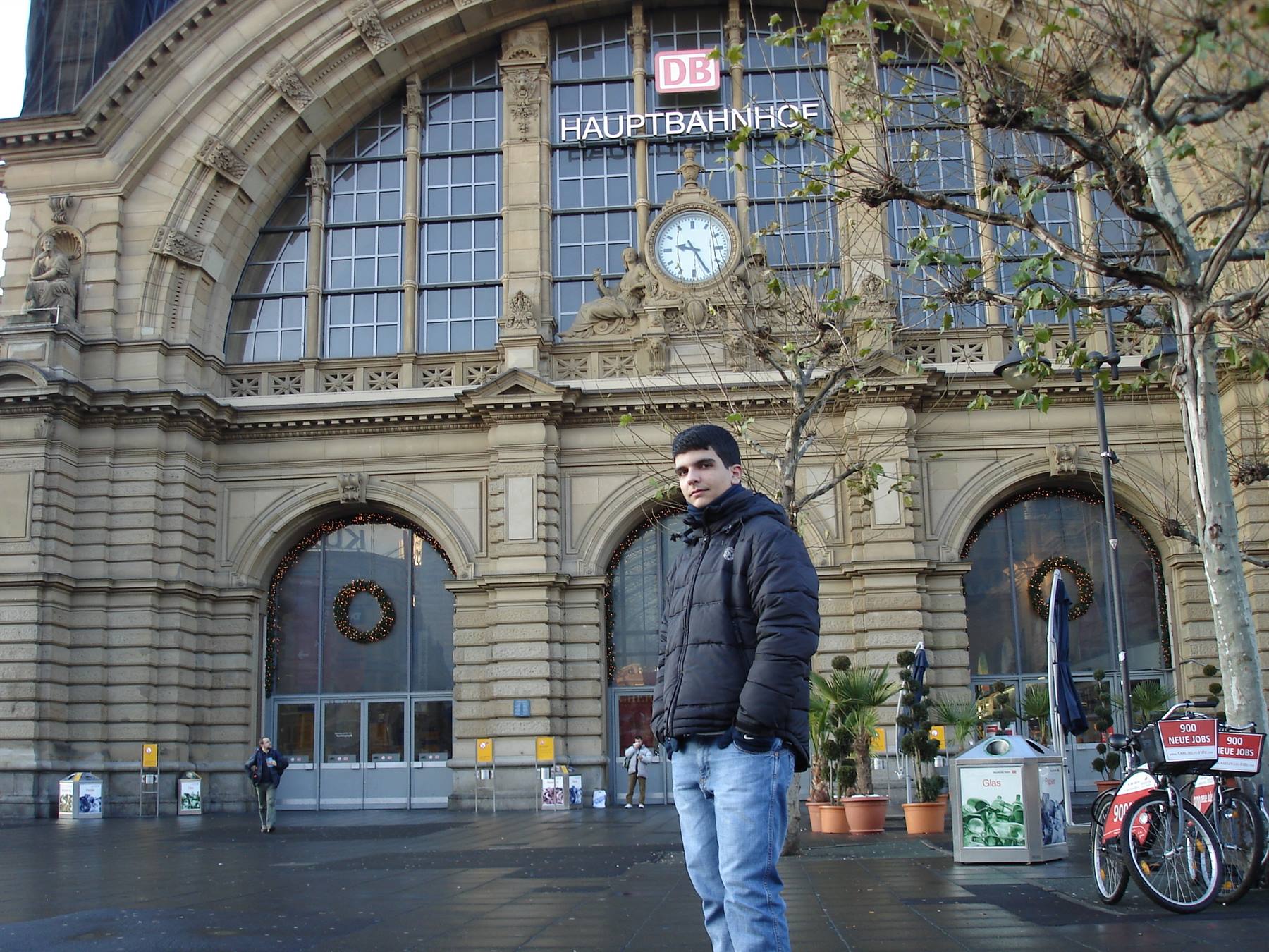 Young man in front of the stone facade of Frankfurt Hauptbahnhof station