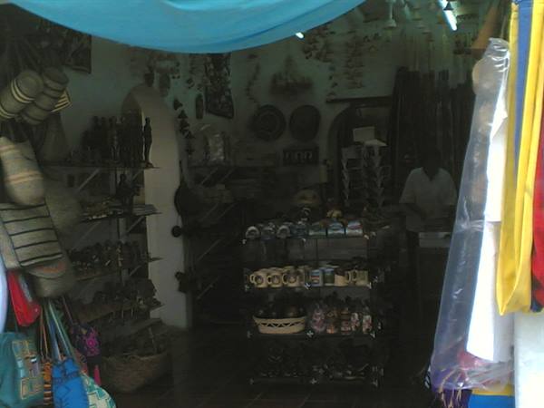 Dim souvenir shop interior, shelves with mugs, woven baskets and colorful bags