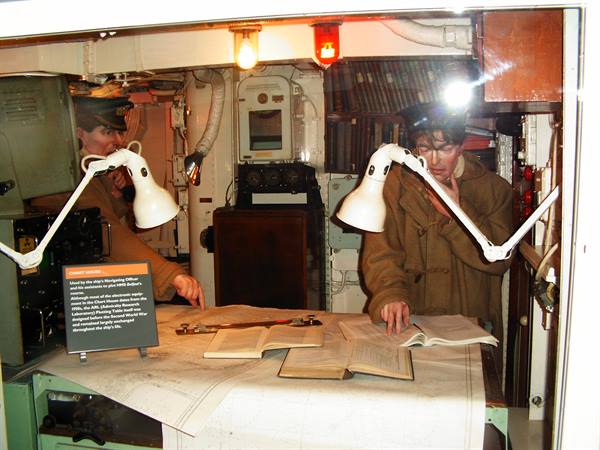 Ship's chart room museum exhibit: mannequins in uniforms study maps under lamps