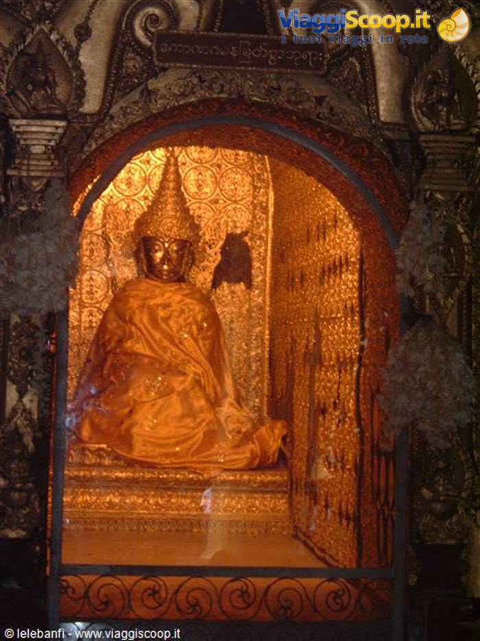 Buddha statue draped in orange cloth inside a gilded decorated niche