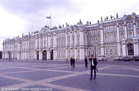 Tourists walk in front of the Winter Palace on Palace Square