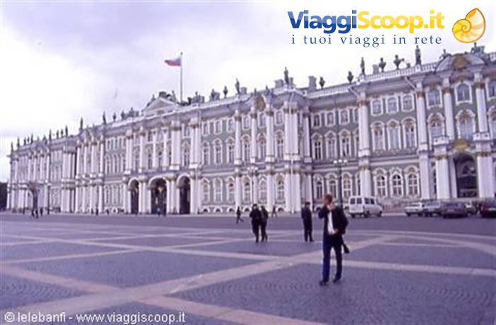 Tourists walk in front of the Winter Palace on Palace Square