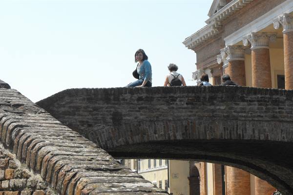 Tourists sitting on the brick arches of Trepponti bridge, Comacchio
