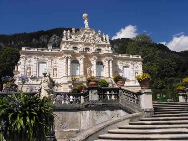 Linderhof Palace, white baroque facade, statues, flower pots and stone staircase