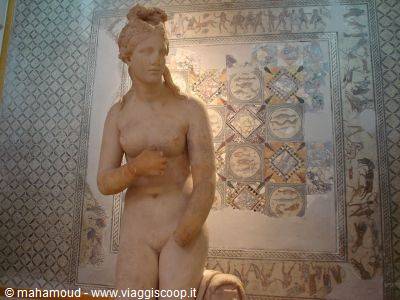 Marble Venus statue standing before a Roman mosaic at the Bardo Museum