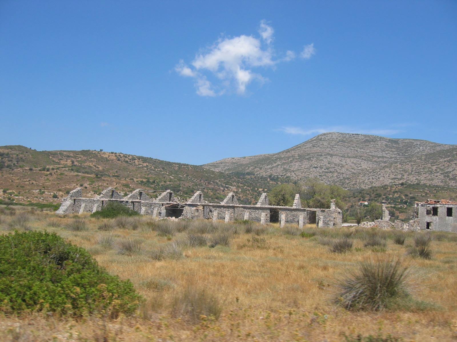 Stone factory ruins among dry shrubs and arid hills