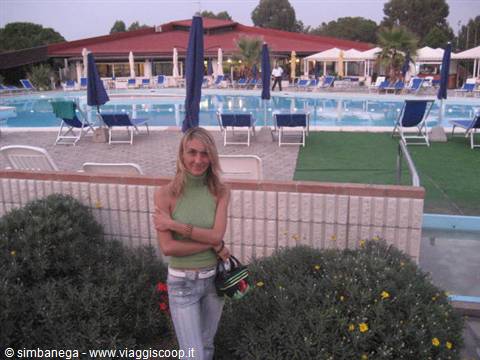 Woman in green top beside the resort pool with umbrellas and loungers