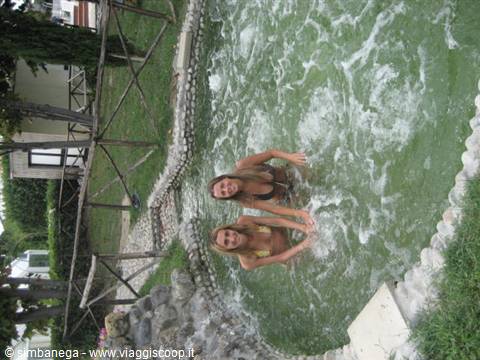 Two smiling girls bathing in a stone-edged thermal pool