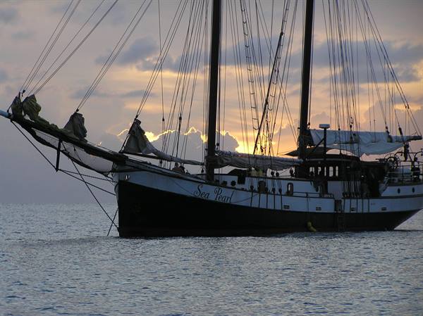The schooner Sea Pearl anchored on calm sea beneath sunset clouds