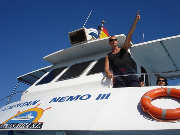 Captain in sunglasses pointing skyward aboard the Capitán Nemo III boat in Ibiza