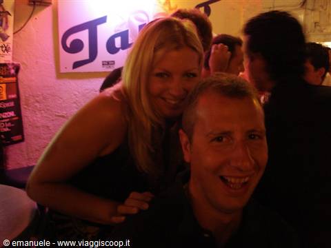 Two smiling friends in a crowded bar with pink lighting