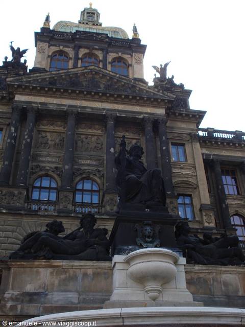 Equestrian statue before the dark facade of the National Museum in Prague