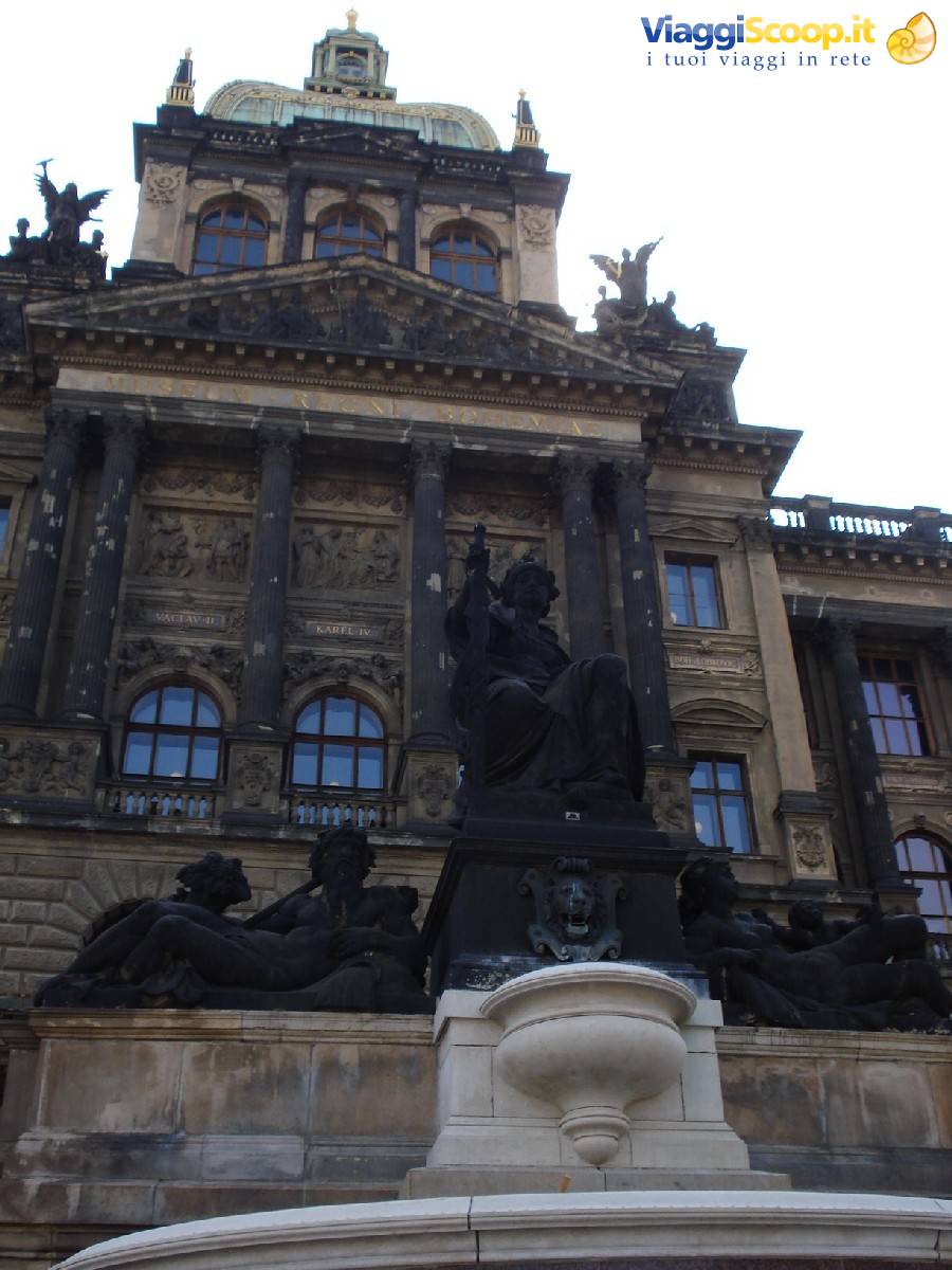 Equestrian statue before the dark facade of the National Museum in Prague