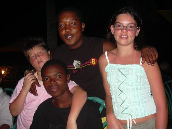 Four teenagers posing together at night, camera flash lighting their smiles