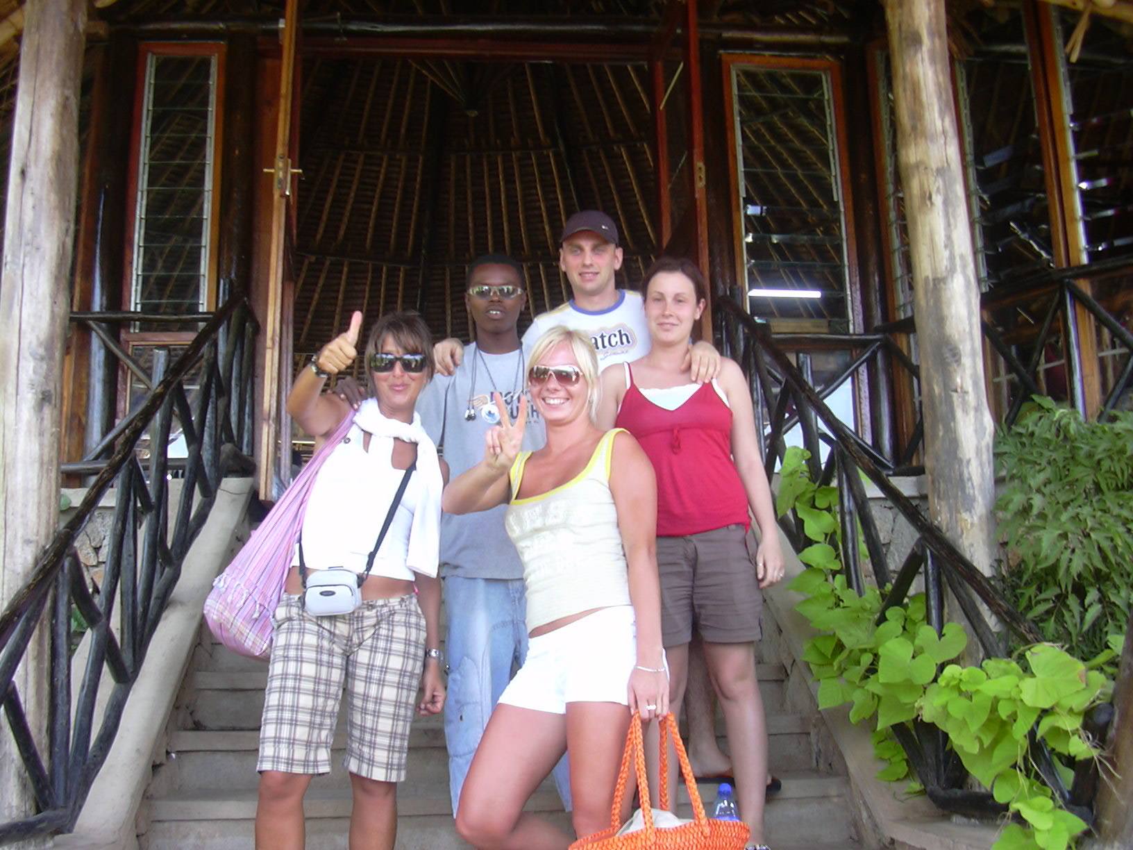 Five tourists posing on wooden steps in front of a lodge