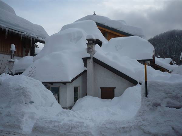 House buried under heavy snow, massive drifts covering the roofs