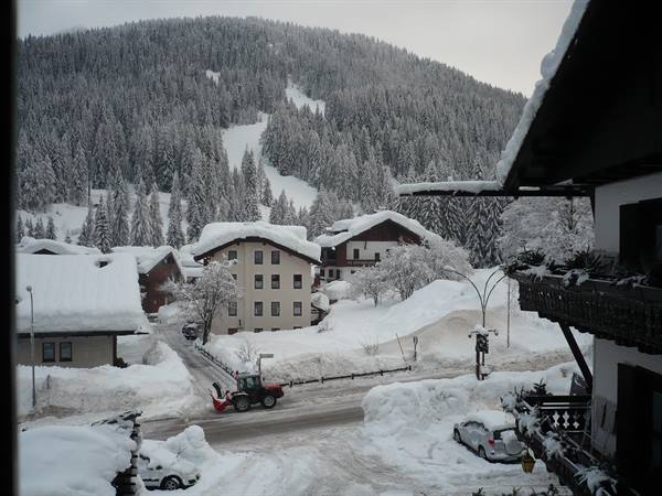 A snow blower clears the snowy road among snow-covered roofs
