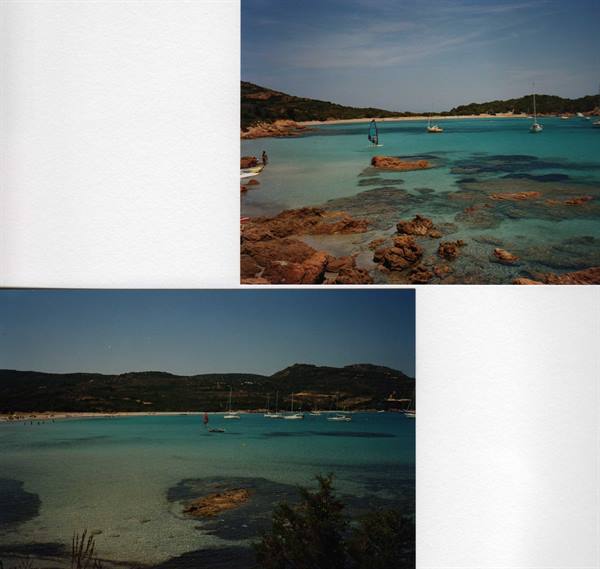 Turquoise bay with pink rocks, anchored boats and a windsurfer