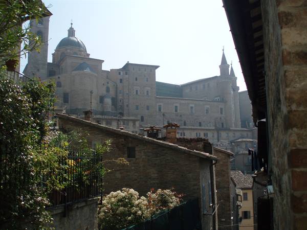 Ducal Palace and cathedral dome above stone rooftops in Urbino
