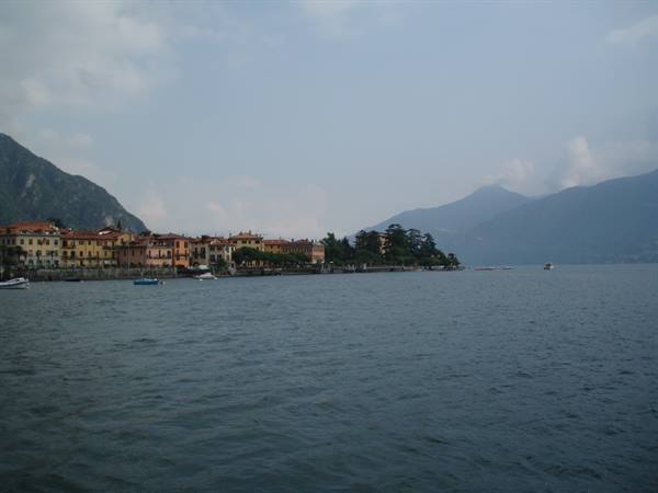 Bellagio lakeside promenade with colorful houses, boats and misty mountains