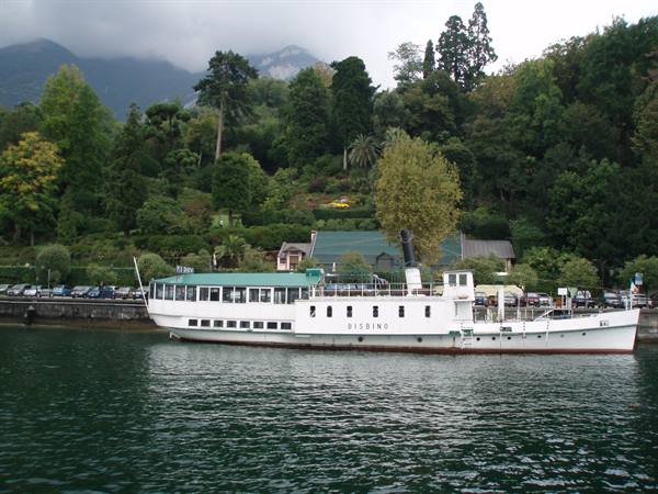 White paddle steamer moored on the lake, green hills and cloudy mountains