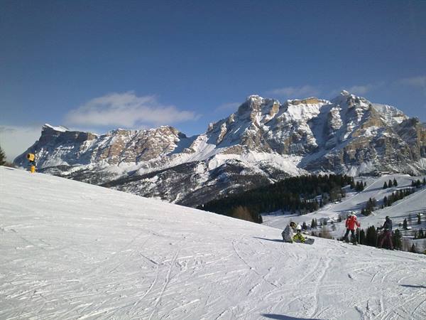 Skiers on snowy slope in front of jagged Dolomite peaks
