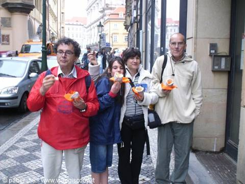 Four people eating trdelník on a cobblestone street in Prague