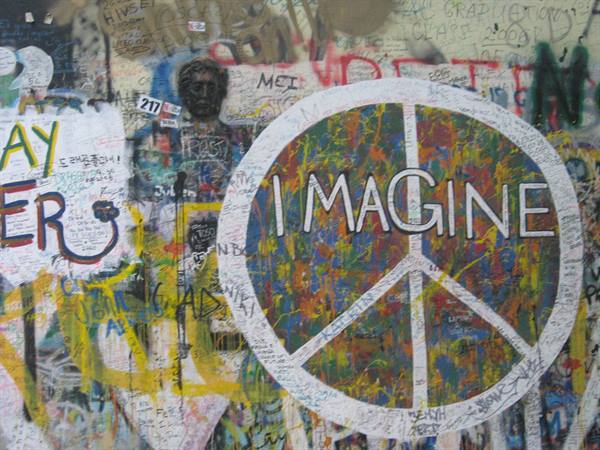 White 'Imagine' graffiti over wall covered with colorful spray-paint messages