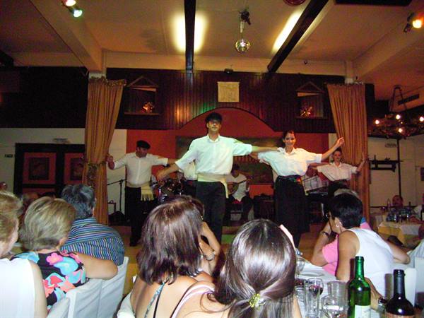 Dancers in white shirts perform for tourists seated at restaurant tables