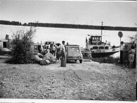 Car and people waiting for the ferry on the sandy riverbank